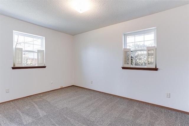 carpeted empty room with a textured ceiling and baseboards