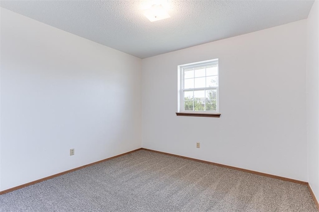 carpeted spare room featuring baseboards and a textured ceiling