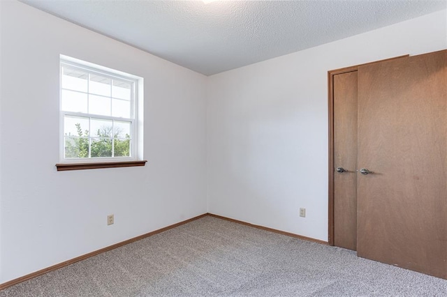 carpeted empty room featuring baseboards and a textured ceiling