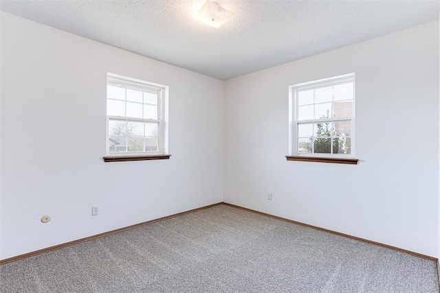 empty room with carpet flooring, baseboards, and a textured ceiling