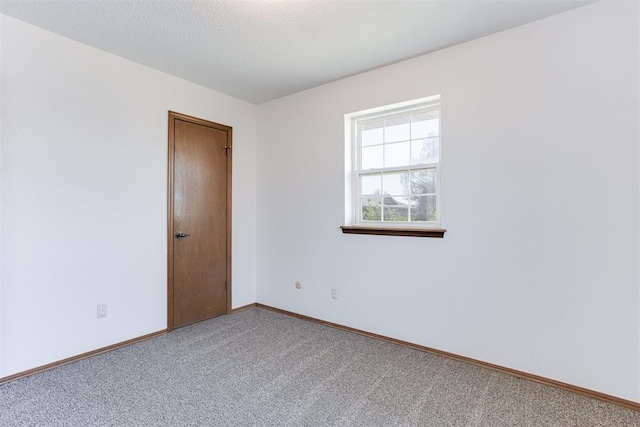 unfurnished room featuring a textured ceiling, baseboards, and carpet floors