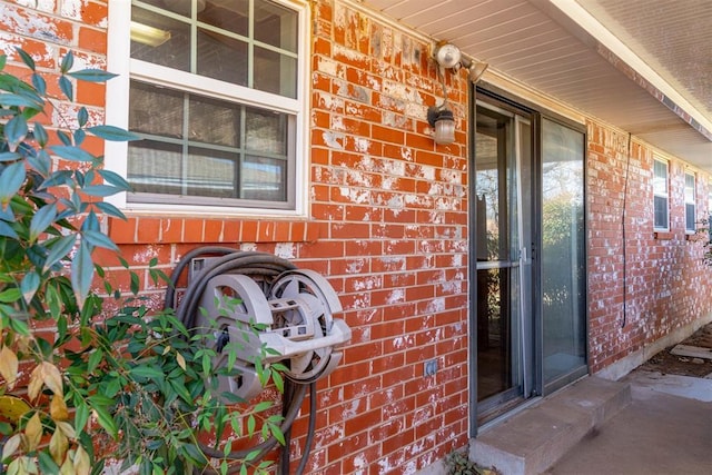 view of exterior entry with covered porch and brick siding