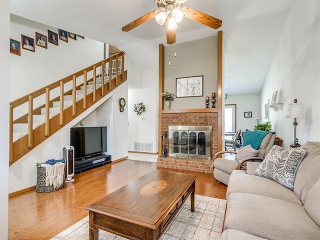 living room featuring wood-type flooring, a fireplace, vaulted ceiling, and ceiling fan