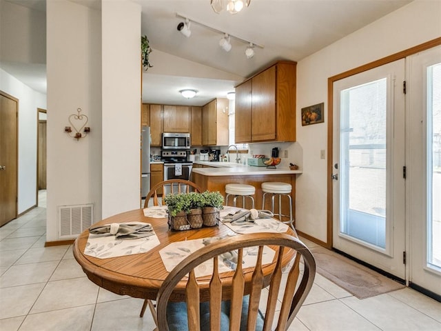 dining area featuring sink, lofted ceiling, and light tile patterned flooring