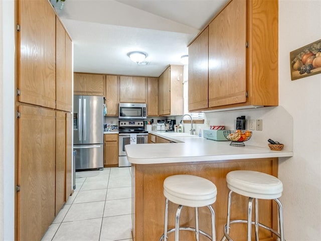 kitchen with sink, stainless steel appliances, kitchen peninsula, and light tile patterned flooring