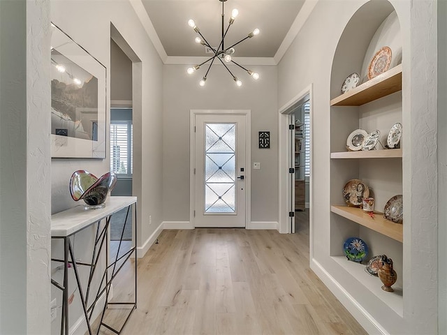 entryway featuring crown molding, a chandelier, and light wood-type flooring