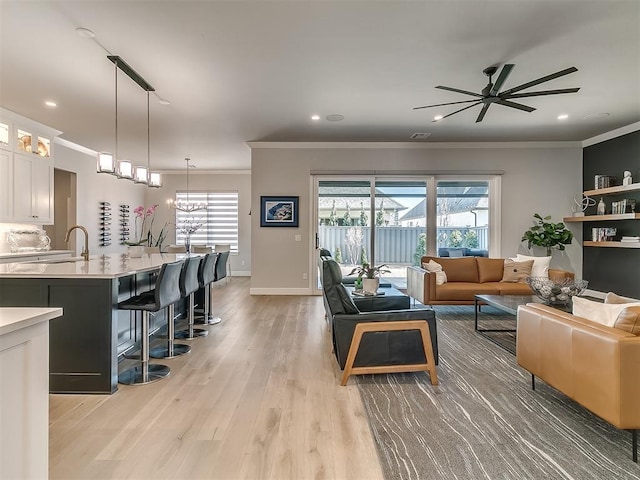 living room with crown molding, light hardwood / wood-style flooring, and ceiling fan with notable chandelier