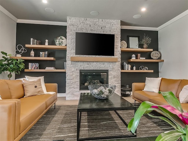 living room featuring ornamental molding, a stone fireplace, hardwood / wood-style floors, and built in shelves