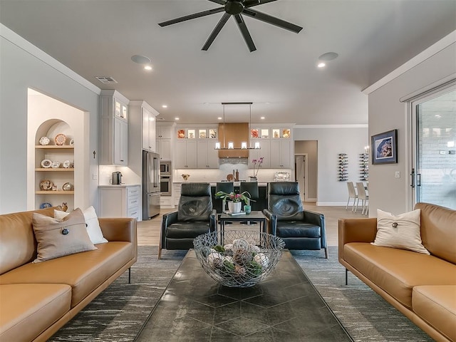 living room with ceiling fan, crown molding, and built in shelves