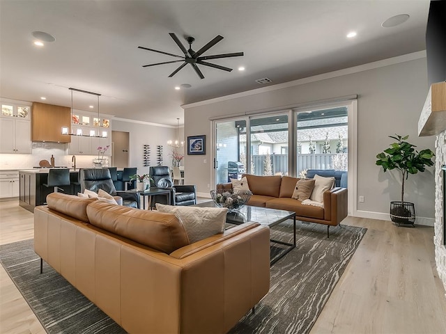 living room featuring ceiling fan, ornamental molding, sink, and light wood-type flooring