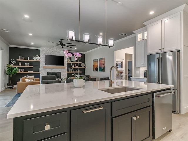 kitchen with white cabinetry, sink, a center island with sink, and ornamental molding