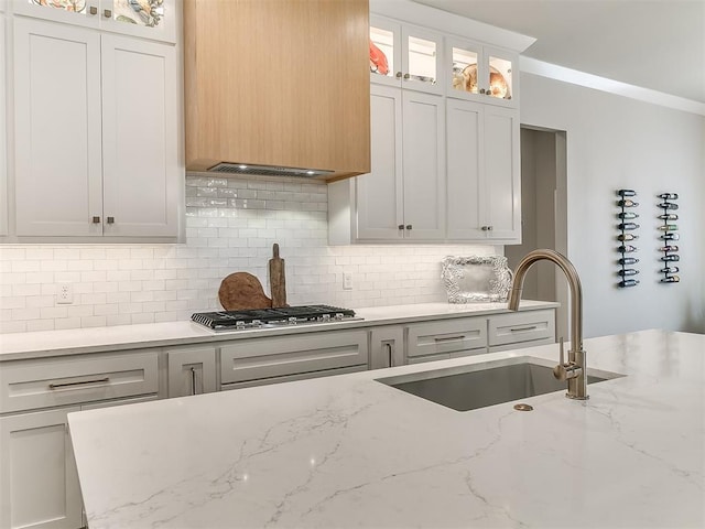 kitchen with sink, stainless steel gas stovetop, light stone countertops, and white cabinets