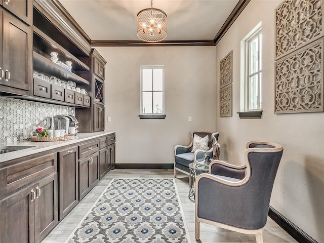 living area featuring a notable chandelier, crown molding, sink, and light wood-type flooring