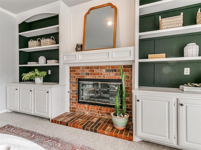 living room with crown molding, a brick fireplace, built in shelves, and light carpet