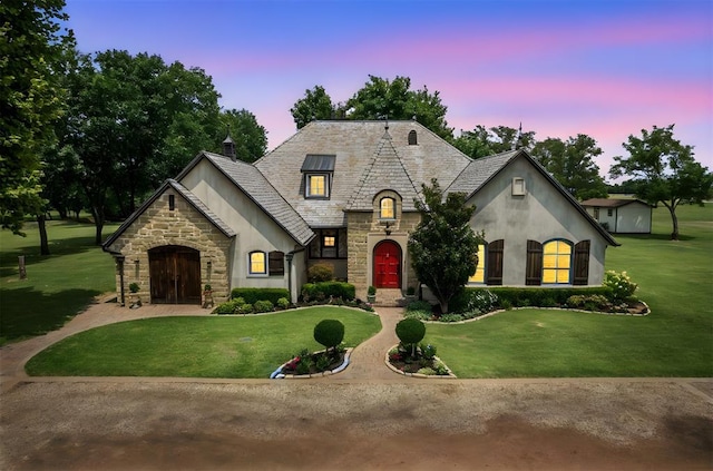 french country inspired facade featuring a yard