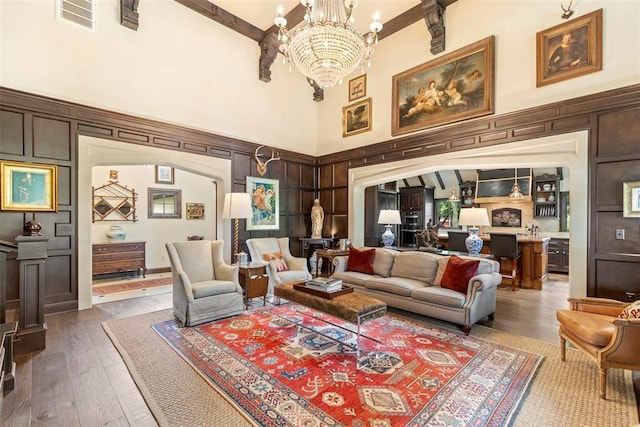 living room with hardwood / wood-style floors, an inviting chandelier, beamed ceiling, and a high ceiling