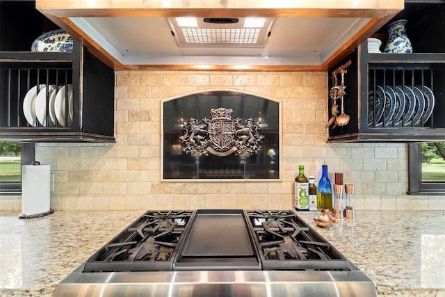 kitchen with decorative backsplash, ventilation hood, gas range, and light stone counters