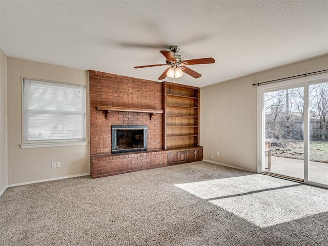 unfurnished living room featuring a brick fireplace, light colored carpet, a textured ceiling, and ceiling fan