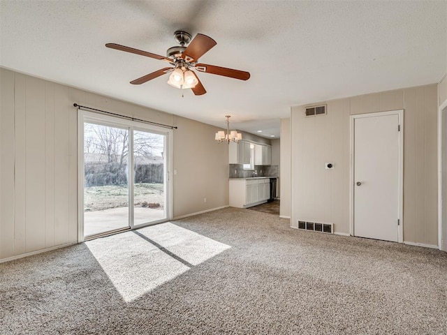 unfurnished living room featuring ceiling fan with notable chandelier, a textured ceiling, and carpet flooring