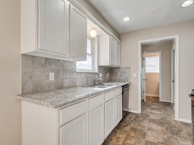 kitchen featuring sink, dishwasher, backsplash, light stone counters, and white cabinets