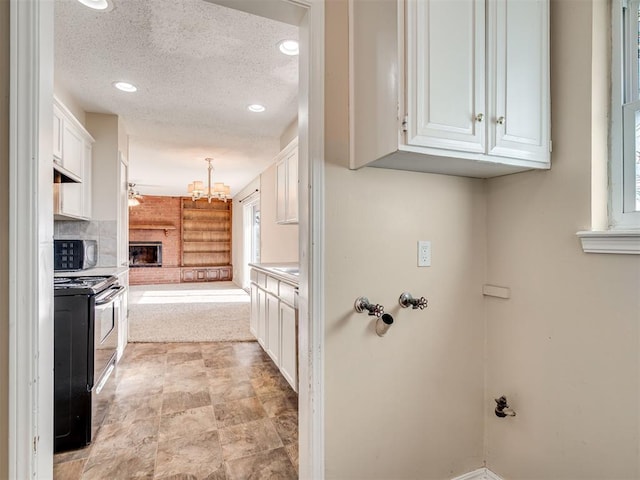 kitchen with white cabinetry, pendant lighting, range with electric cooktop, and a textured ceiling