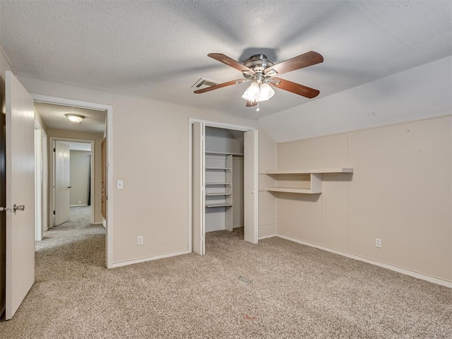 unfurnished bedroom with light carpet, a textured ceiling, vaulted ceiling, and ceiling fan