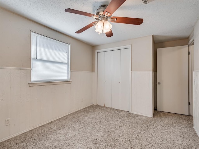 unfurnished bedroom featuring light carpet, a textured ceiling, ceiling fan, and a closet