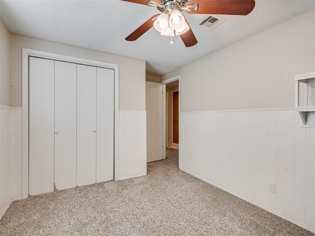 unfurnished bedroom with light colored carpet, a closet, and ceiling fan