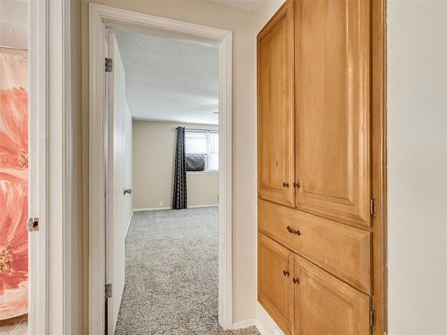 hall with light colored carpet and a textured ceiling