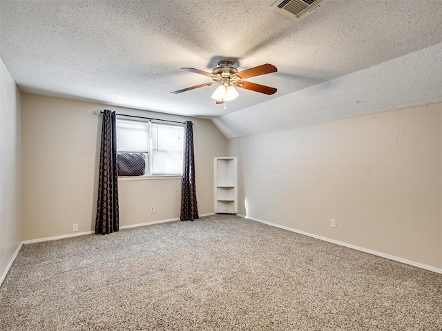 additional living space with ceiling fan, lofted ceiling, carpet, and a textured ceiling