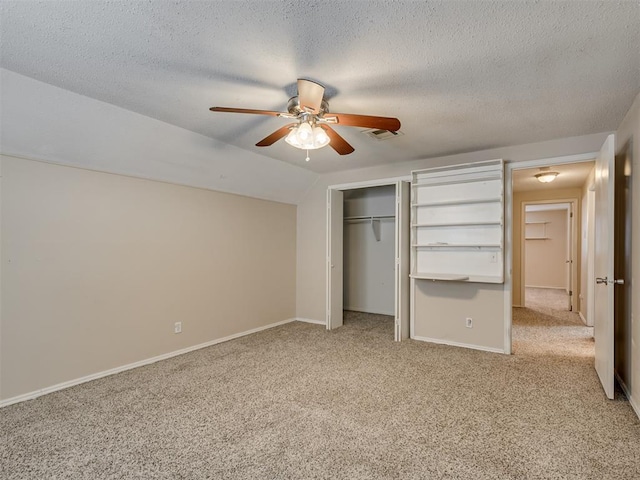 unfurnished bedroom featuring light carpet, vaulted ceiling, a closet, and ceiling fan