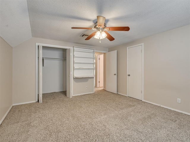 unfurnished bedroom with lofted ceiling, light carpet, a textured ceiling, and ceiling fan