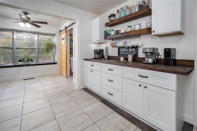 kitchen with wooden counters, white cabinetry, ceiling fan, and a barn door