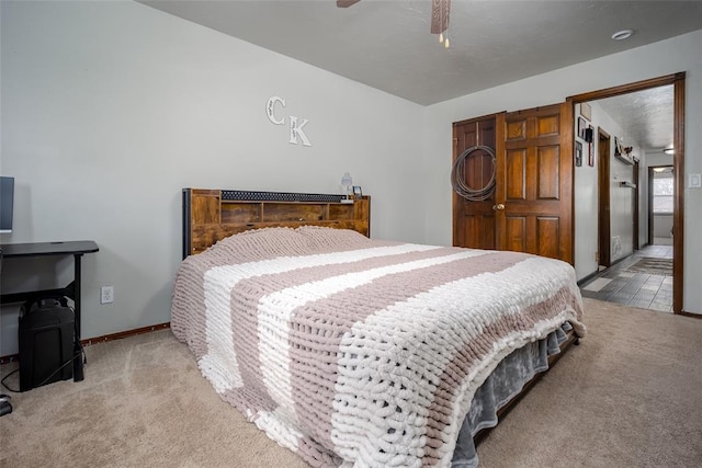 bedroom with light colored carpet, ensuite bathroom, and ceiling fan