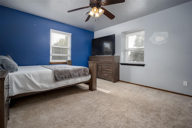 bedroom with ceiling fan, light colored carpet, and multiple windows