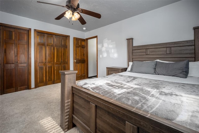 bedroom with light colored carpet, two closets, and ceiling fan