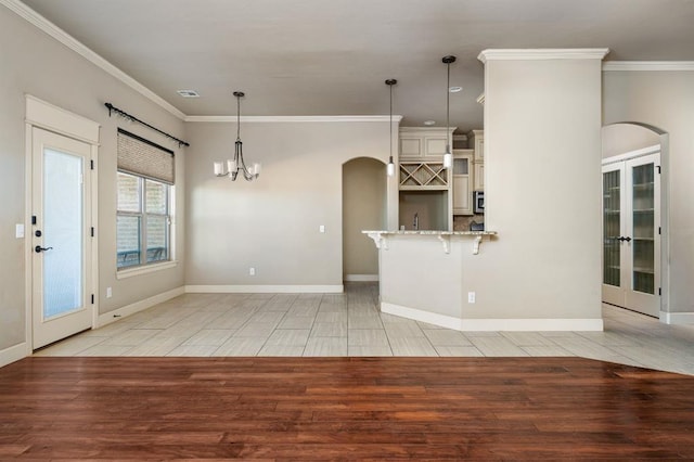 kitchen with light tile patterned floors, crown molding, hanging light fixtures, and a kitchen bar