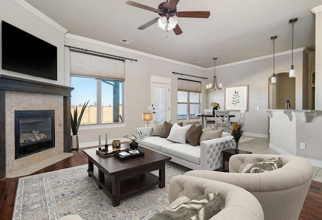 living room featuring crown molding, plenty of natural light, hardwood / wood-style floors, and a tile fireplace