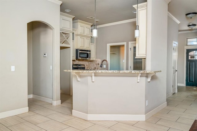 kitchen with a breakfast bar, sink, crown molding, hanging light fixtures, and cream cabinetry