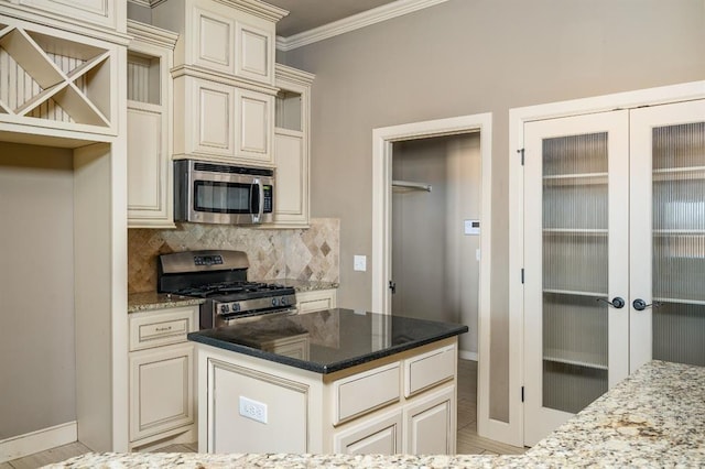 kitchen featuring appliances with stainless steel finishes, dark stone countertops, ornamental molding, cream cabinetry, and french doors