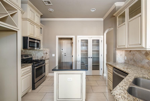 kitchen with tasteful backsplash, crown molding, dark stone counters, and appliances with stainless steel finishes