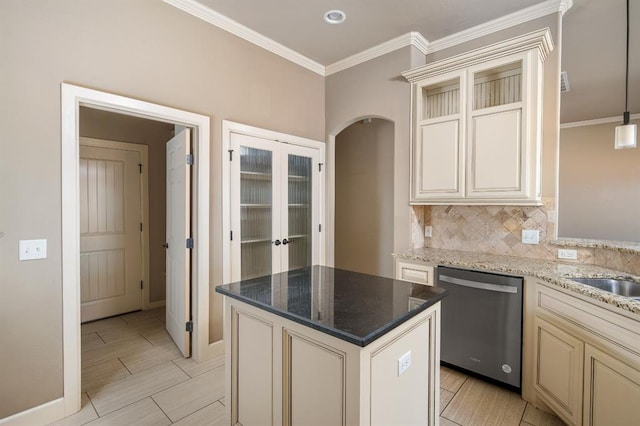 kitchen featuring hanging light fixtures, ornamental molding, a center island, stainless steel dishwasher, and cream cabinets