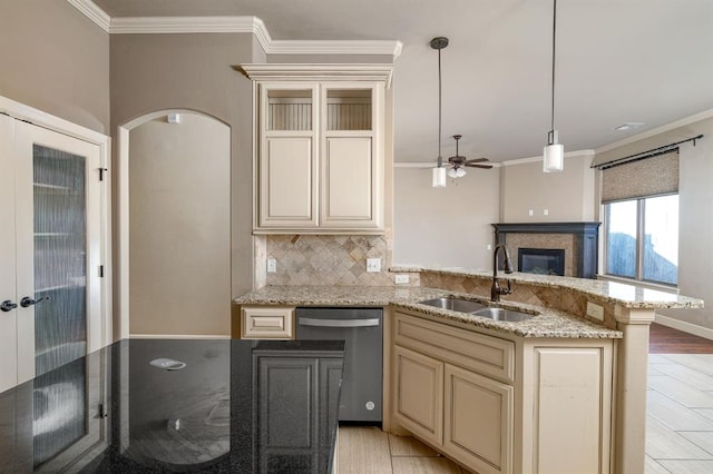 kitchen featuring sink, stainless steel dishwasher, pendant lighting, decorative backsplash, and cream cabinetry