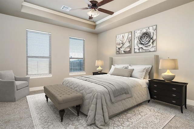 carpeted bedroom featuring ceiling fan, ornamental molding, and a tray ceiling