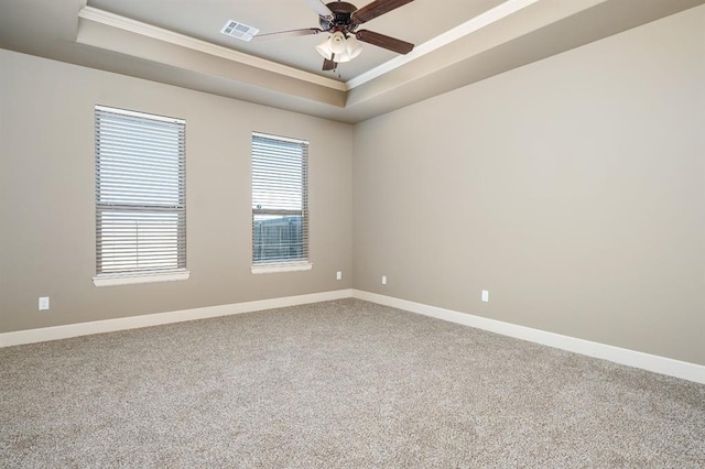 carpeted empty room featuring ornamental molding, ceiling fan, and a tray ceiling