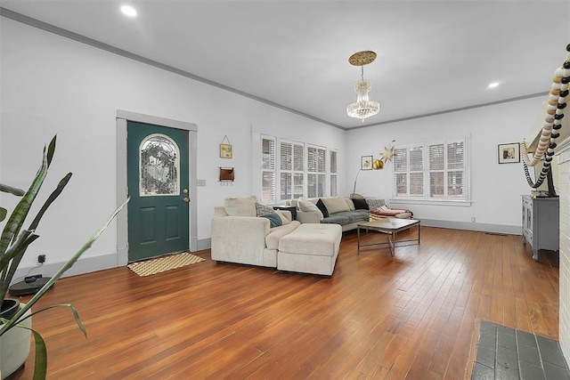 living room with an inviting chandelier, crown molding, and wood-type flooring