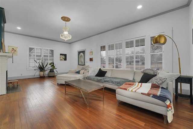 living room featuring plenty of natural light, dark wood-type flooring, an inviting chandelier, and a fireplace