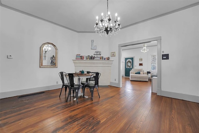 dining room with an inviting chandelier, hardwood / wood-style floors, and crown molding