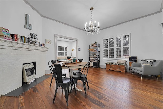 dining room featuring dark wood-type flooring, ornamental molding, heating unit, and a notable chandelier