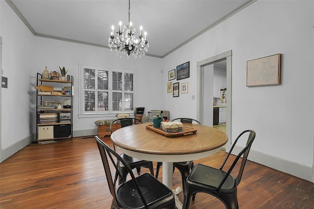 dining area featuring dark wood-type flooring, ornamental molding, and a notable chandelier